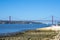 Panoramic view of Lisbon\\\'s red metal 25 de April steel suspension bridge like the Golden Gate, from the beach coast.