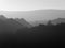 Panoramic view of a misty tree covered mountain landscape with hills in silhouette in different shades of of grey
