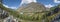 Panoramic view of a mountain valley with a river. Forest, blue sky and hillside trail