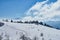 Panoramic view of the mountains. In the foreground there is a snow-covered glade, on the middle a forest, on the far a cliff, on t