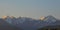 Panoramic view of the mountains of the Zailiysky Alatau over the houses on the slope during the summer morning sunrise.