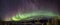 Panoramic view of multicolored Aurora curved above Scandinavian mountains and frozen lake, very cold winter night, deep clear sky