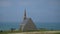 Panoramic view of old church on Etretat peak at Manneporte and Amont gate on background of sky and water. Unrecognizable