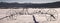 Panoramic view of old worn wagon wheels stuck in the snow with mountains in the background