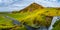 Panoramic view over camping site with tents and cars in front of famous Skogarfoss waterfall, while hiking in Iceland, summer