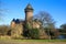 Panoramic view over moat on medieval water castle and defensive tower with bare trees in winter against blue sky - Krefeld Linn