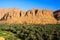 Panoramic view over palm grove oasis on isolated clay house village, rugged steep limestone mountain