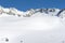 Panoramic view over a snowy slope with hikers