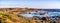 Panoramic view of the Pacific Ocean coastline on a sunny winter day; Elephant seals visible on the sandy beach; San Simeon,