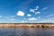 Panoramic view of riverbank with reflections of white fluffy clo