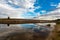 Panoramic view of riverbank with reflections of white fluffy clo