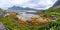 Panoramic view from the rocky shore to the bay overgrown with marine plants. Mountains under the clouds surround the fjord.