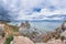 Panoramic view of the sacred Shamanka rock against the backdrop of a dramatic sky and stormy lake. Cape Burkhan, Olkhon Island,