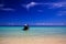 Panoramic view from sand beach over shallow turquoise water and isolated thai long-tail boat into endless horizon with blue sky -