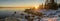 Panoramic view of Scenic Winter Sunset over sea, big stones at coastline and forest of peninsula Kont, Umea, Sweden. Winter