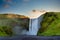 Panoramic view of the Skogafoss waterfall in Iceland. In the morning, the sunrise from behind a mountain