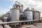 Panoramic view of a sugar factory\\\'s exterior, with storage silos, smokestacks, and a network of pipes and conveyors