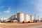 Panoramic view of a sugar factory\\\'s exterior, with storage silos, smokestacks, and a network of pipes and conveyors