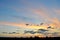 A panoramic view of the sunset sky and clouds, beautifully illuminated by the evening sun, the silhouette of several trees