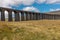 A panoramic view of the sweeping majestic Ribblehead Viaduct stands tall above the Ribble Valley, Yorkshire, England carrying the