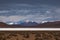 Panoramic view of three snow capped volcanoes.