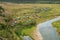 Panoramic view of tine european village hidden in hills on bank of narrow river, forest on background. Rural, picturesque rustic p