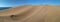 Panoramic view to sand dunes and ocean behind them