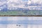 Panoramic view towards green hills and snowy mountains on a cold winter day taken from the shores of a pond in south San Francisco