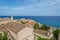 Panoramic View of Traditional House Rooftops in Medieval Castle Town of Monemvasia. Deep Blue Sea and Sky in the Horizon.