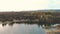 A panoramic view of a tranquil mountain lake with a small cottage beside it at sunset.