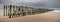 Panoramic view of vertical wooden planks in the sand of an unfinished wooden dock at the beach