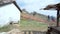 Panoramic view of village. Old dilapidated black wooden boat with a one-storey house, a well and a hill. Old wooden