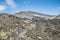 : Panoramic view of volcano Etna against an intense blue sky. Horizontal view of the central crater. A row of people trying to
