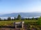 A panoramic view on a wooden bench on an Alpine meadow in high mountains during an early morning. There is a fog