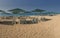 Panoramic view of a yellow sandy beach with white sunbeds