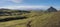 Panoramic volcanic landscape of green Storasula mountain with lush moss, footpath and blue creek water between Emstrur