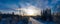 Panoramic wide scenic aerial photo over forest winter road with windmills standing in row at the left side in forest. Road at the