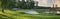 Panorarmic view of golf green with traps and trees