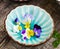 Pansy flowers in a blue cup on wooden background