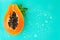 Papaya fruit on blue background with water drops, fresh exotic fruits border design. Half of fresh organic Papaya