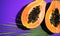 Papaya fruit on tropical violet background with palm tree leaf. Halved fresh organic Papayas