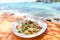 Papaya salad with blue crab on table and beach sea coast background / Thai food raw crab spicy salad seafood and vegetable food on