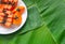 Papaya slices on white plate with green banana leaves background, copyspace, flat lay