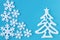 Paper applique with white carved snowflakes and christmas tree on blue background. Postcard of minimalist style. New year handmade