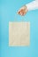 Paper bag at arm`s length, brown craft bag for takeaway isolated on blue background. Packaging template layout with space for