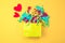 Paper bag with colored streamers on a bright yellow background Red heart concept of Valentine& x27;s day