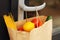 A paper bag with food from delivery on the handle of the front door, closeup