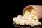 Paper bag with fresh popcorn, black background