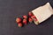 Paper bag with fresh red strawberries. Fresh strawberries in a small bag on a wooden style surface. Small group of strawberries on