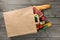 Paper bag full of different food on wooden background